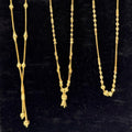 Three gold necklaces on a black stand