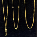 Three gold necklaces on a black velvet stand