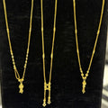 Three gold necklaces on a black stand
