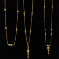 Three gold necklaces on a black stand