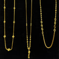 Three gold necklaces on a black stand