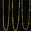 Three gold necklaces on a black stand