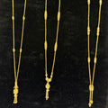 Three gold necklaces on a black stand