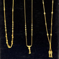 Three gold necklaces on a black stand
