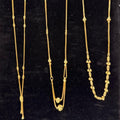 Three gold necklaces on a black stand