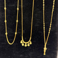 Three gold necklaces on a black stand