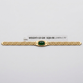 A gold bracelet with a central green oval stone and decorative side details, displayed on a light gray background with a small label showing weight and dimensions.
