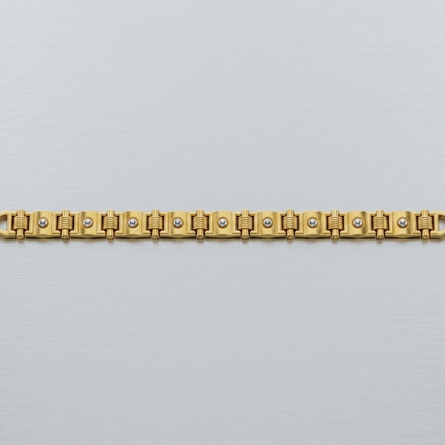 A gold-plated link bracelet with small clear stones set into the center of each link, displayed horizontally on a light gray textured background.