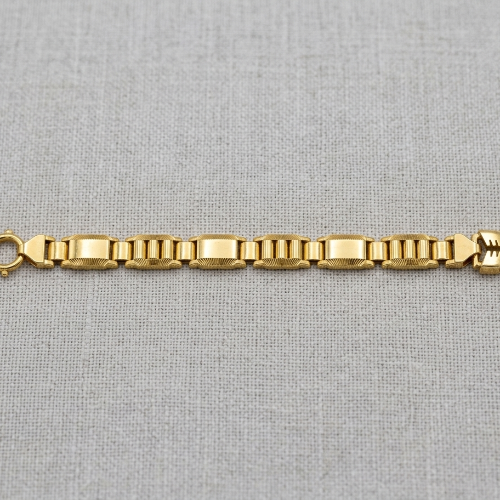 A yellow gold link bracelet with a lobster clasp and a decorative bow-shaped end, displayed horizontally on a textured light gray fabric background.