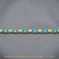 A gold-plated bracelet featuring turquoise blue enamel panels with yellow lightning bolt motifs, displayed on a textured gray fabric background with product specifications printed at the bottom.