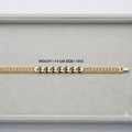 A gold-toned bracelet with a textured geometric pattern and black diamond-shaped accents, displayed horizontally inside a light gray jewelry box. Text in the center reads 'WEIGHT=14 GM BQB=1053'.