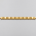 A gold-toned metal link bracelet with a textured pattern on the links, displayed horizontally on a brushed silver metal surface.