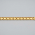 A gold-colored metal link bracelet with a woven chevron pattern, displayed horizontally against a neutral light gray background.
