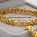 A gold-toned pyramid-link bracelet displayed inside a light gray jewelry box. The image includes a text overlay detailing the product's weight, length, and width, along with a style code.