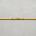 A gold chain bracelet with a textured, braided design and decorative end caps, displayed horizontally on a neutral gray background.