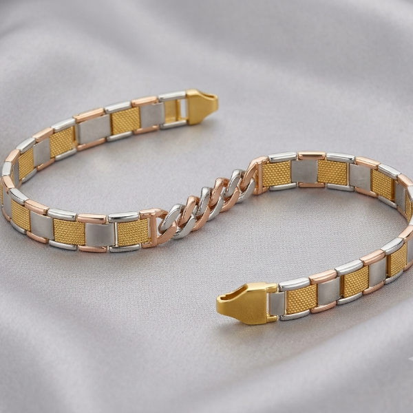 A two-tone metal bracelet with alternating gold, silver, and rose gold textured and smooth rectangular links, displayed on a soft gray satin fabric background.