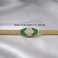 A gold-tone watch band with a decorative center section paved with green emerald-cut stones and a central diamond, displayed on a draped silver satin fabric. Text overlay reads 'WEIGHT=10 GM LEANTH=7.