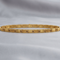 A gold link bracelet with a segmented, geometric design featuring textured and polished rectangular links, displayed on a soft, draped gray fabric background.