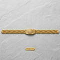 A gold-tone metal watch band with a central shield-shaped emblem, displayed horizontally on a light gray textured background. A small gold tag below reads 'FGB-113'.
