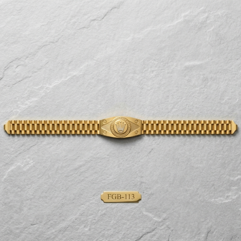 A gold-tone metal watch band with a central shield-shaped emblem, displayed horizontally on a light gray textured background. A small gold tag below reads 'FGB-113'.