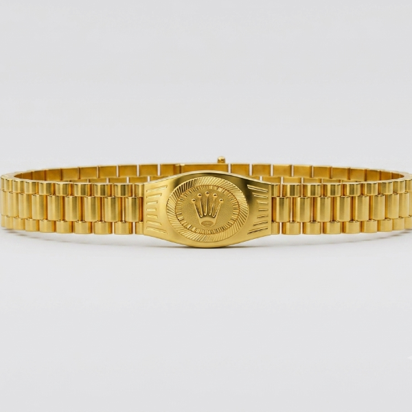 A gold-tone metal link bracelet watch band with a central oval plate featuring a crown emblem, photographed against a clean light gray background.