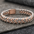 A braided metal bracelet with alternating silver and rose gold links, featuring a rectangular clasp, displayed on a textured gray felt surface.