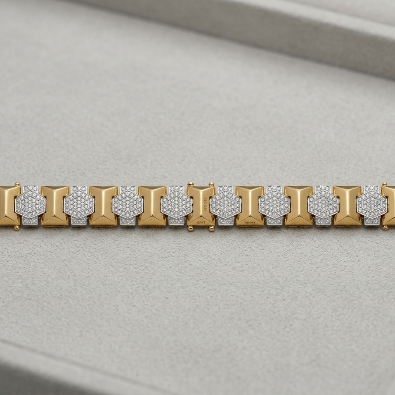 A two-tone yellow gold and silver-toned bracelet with pavé-set clear stones, displayed on a light gray textured jewelry box.