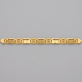 A gold link bracelet with a combination of polished rectangular links and textured geometric patterns, displayed horizontally on a solid gray background.