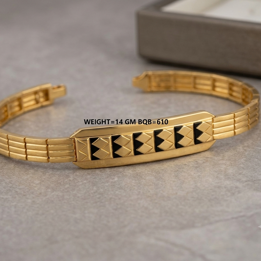 A gold-plated metal link bracelet with a central rectangular plate featuring black geometric diamond patterns, resting on a gray textured surface.