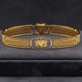A gold-toned metal bracelet with a textured, woven mesh-like pattern and a central decorative clasp, displayed on a dark gray velvet jewelry box against a dark gray background.