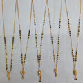 Set of five gold necklaces with black beads on a gray background