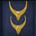 A pair of ornate gold-toned traditional necklace sets displayed on a dark navy blue textured background.