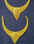 A pair of ornate gold crescent-shaped traditional jewelry pieces with intricate filigree detailing, displayed on a dark textured background.