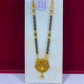 A gold and black beaded necklace with an ornate gold pendant, displayed on a white stand against a dark red background.