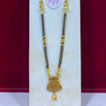 A gold and black beaded necklace with a decorative gold pendant, displayed on a white jewelry stand against a dark red background. A small white price tag is attached near the top.