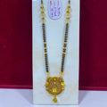 A gold and black beaded necklace with an ornate gold pendant, displayed on a white stand against a dark red background. A small white tag with handwritten measurements is attached to the necklace.