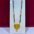A traditional Indian gold and black bead necklace displayed on a white jewelry stand against a dark red background.