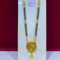 A gold and black beaded necklace with an ornate gold pendant, displayed on a white stand against a dark red background. A white product tag is attached to the necklace.