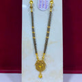 A gold and black beaded necklace with a detailed gold pendant, displayed on a white stand against a dark red background. A white price tag is attached to the necklace.