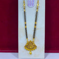 A traditional Indian gold and black bead necklace with a detailed gold pendant, displayed on a white stand against a dark red background.