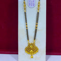 A gold and black beaded necklace with an ornate gold pendant, displayed on a white vertical stand against a dark red background. A small white tag with red text is attached near the top.