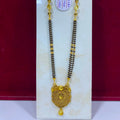 A traditional Indian gold and black bead necklace (manglik) with a detailed gold pendant, displayed on a white stand against a dark red background.