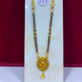 A gold and black beaded necklace with a decorative gold pendant, displayed on a white jewelry stand against a dark red background. A white price tag is attached near the top.