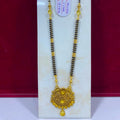 A traditional Indian gold and black beaded necklace with a detailed gold pendant, displayed on a white stand against a dark red background.