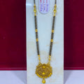 A traditional Indian gold and black beaded necklace with a detailed gold pendant, displayed on a white stand against a dark red background.