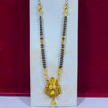 A traditional Indian gold-plated necklace with a black bead chain and an ornate gold pendant, displayed on a white stand against a dark red background.