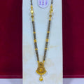 A traditional Indian gold and black beaded necklace (Magga) with a detailed gold pendant, displayed on a white jewelry stand against a dark red background.