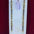 Two gold and black beaded necklaces on a white card with a red background