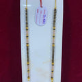 Two gold and black beaded necklaces on a white card with a red background