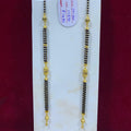 Two black beaded necklaces with gold accents on a white card against a red background.